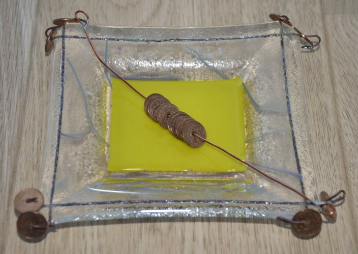 Glasaskebæger gult med mønter på trægulv
